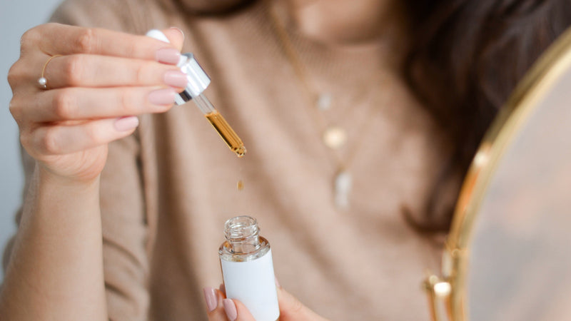 Femme appliquant un sérum K-beauty avec un dropper, ambiance rituel skincare matinal